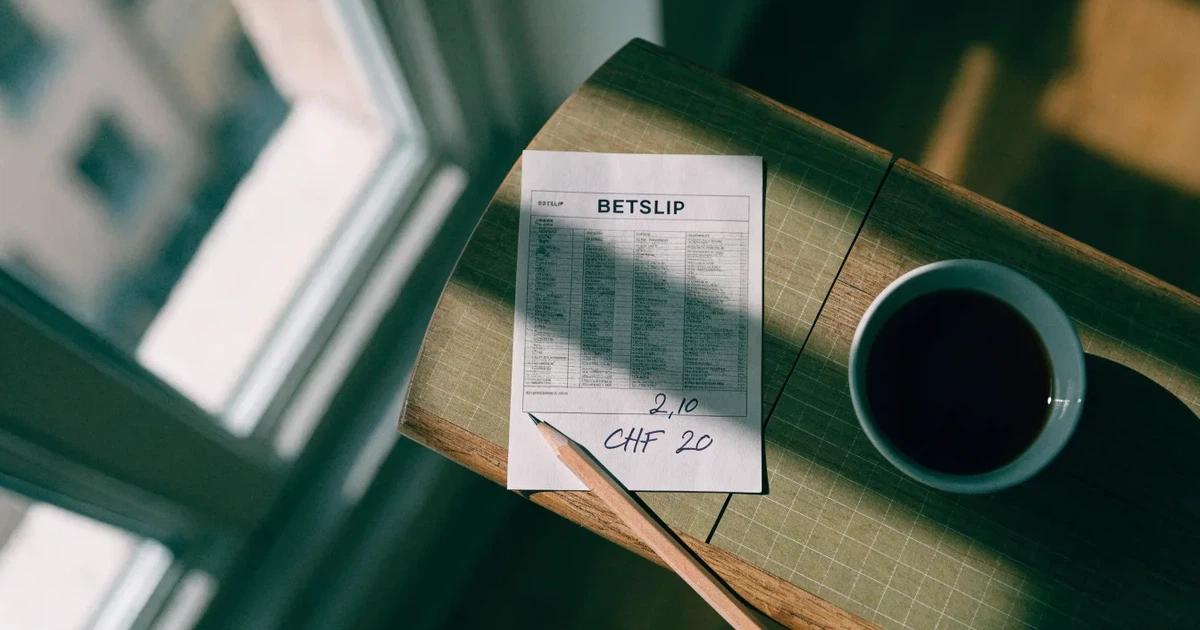 Ein Taschenrechner und ein Bleistift liegen auf kariertem Papier neben einer Tasse Kaffee, ein Fensterplatz mit Tageslicht.
