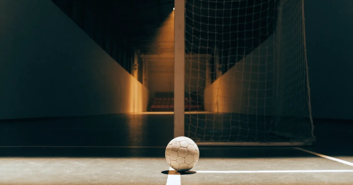 Ein Tor mit dicht gespanntem Netz steht in einer grossen Halle, davor liegt ein Handball auf der Torraumlinie.